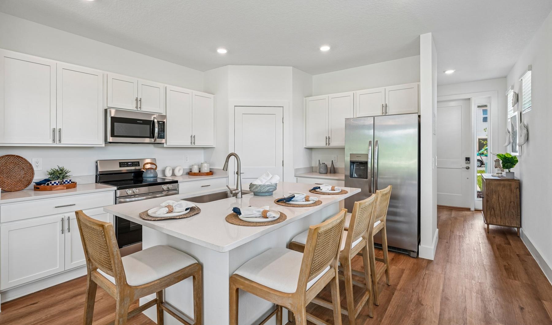 a kitchen with white cabinets and chairs