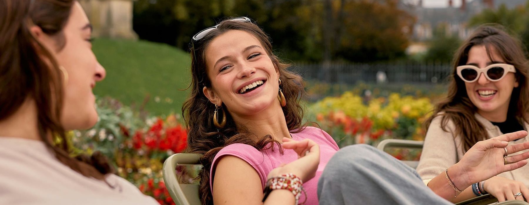 Three women sitting in chairs next to a garden and laughing.